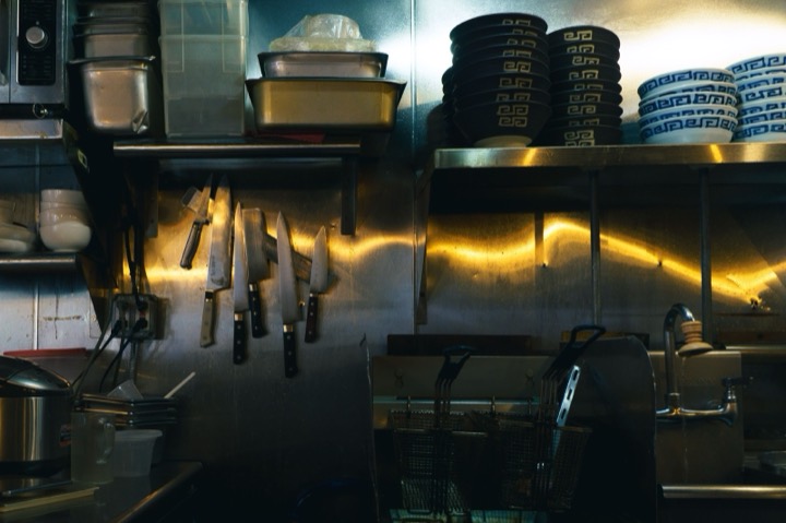 A restaurant kitchen with knives on a magnetic strip and stacked bowls