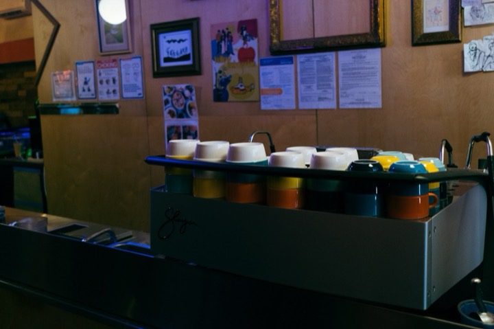 A restaurant counter with condiment containers and framed photos on the wall