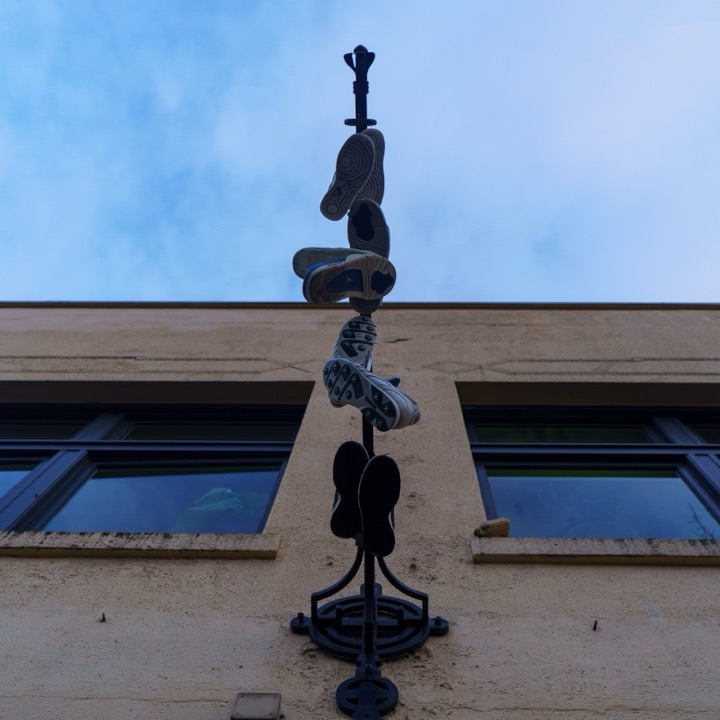 Shoes hanging from a pole against a blue sky