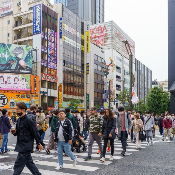 Crowds crossing a Tokyo street under anime billboards