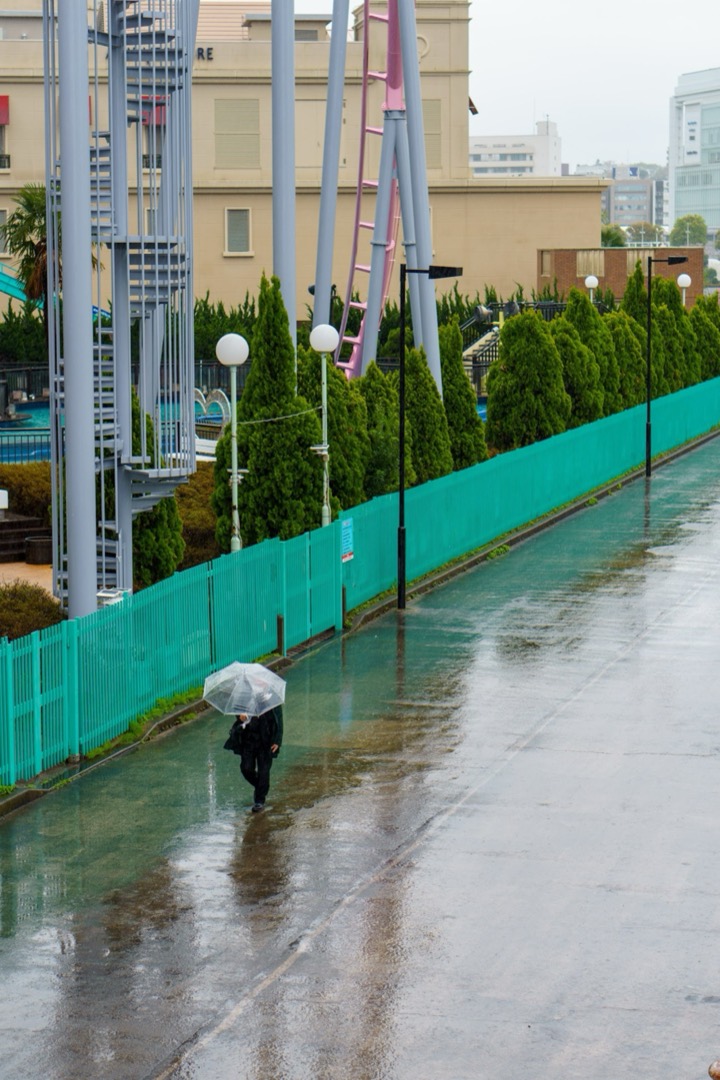 A person with an umbrella walking along a rainy elevated path