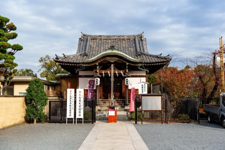 A temple gate at the end of a stone path under a clear sky