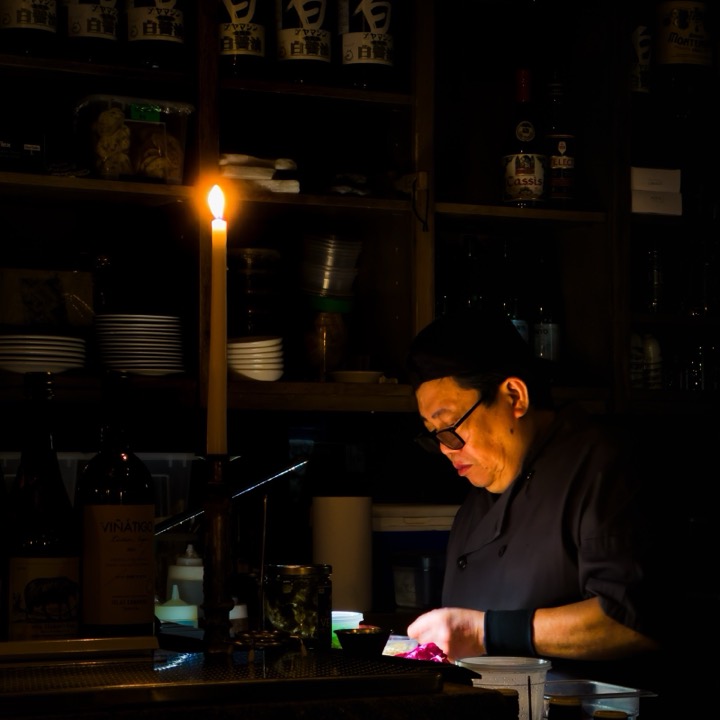 A chef working by candlelight behind a restaurant counter